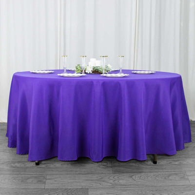 Purple round tablecloth draped over a table with elegant dining setup.