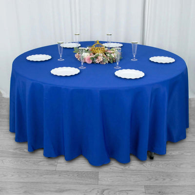 Round blue tablecloth with white plates and floral centerpiece.
