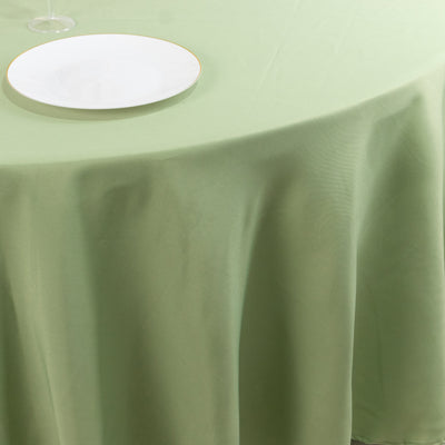 Green tablecloth draping over a round table with a white plate on top.