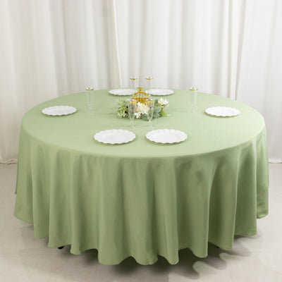 Round green tablecloth with white plates arranged on a round table.