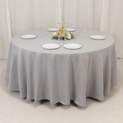 Round gray tablecloth on a round table with decorative plates and centerpiece.