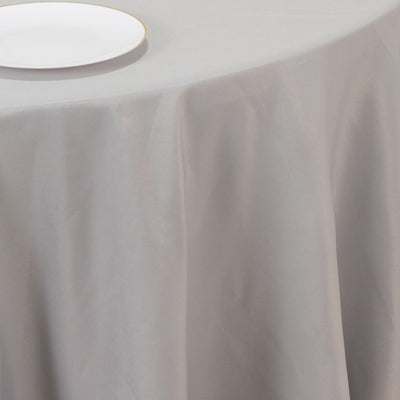 Gray tablecloth draped over a table with a white plate on top.