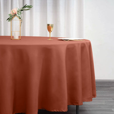Elegant rust-colored tablecloth with gold accents and floral centerpiece.