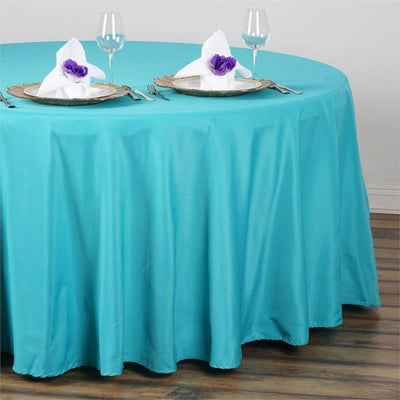 Turquoise tablecloth draped over a round table set for dining.