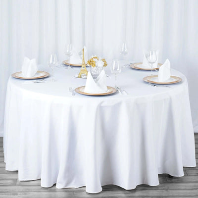 Elegant round dining table set with white tablecloth and decorative elements.