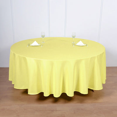 Yellow round tablecloth on a wooden table set for dining.