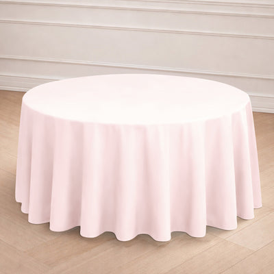 Round pink tablecloth draped over a round table in a simple setting.
