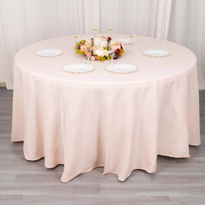 Round table with a soft pink tablecloth and floral centerpiece.