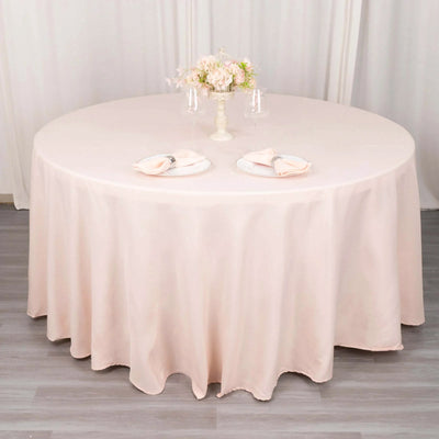 Round blush tablecloth draped elegantly over a table with floral centerpiece.