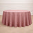 Round pink tablecloth draped over a table in a simple setting.
