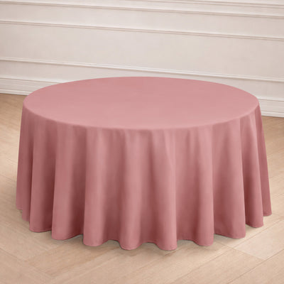 Round pink tablecloth on a wooden floor with a neutral backdrop.