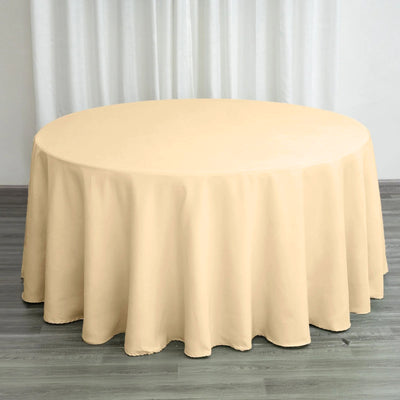 Round beige tablecloth draped over a table in a staged setting.