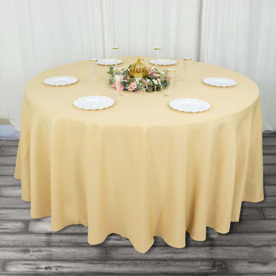 Round table with a beige tablecloth and decorative centerpiece.