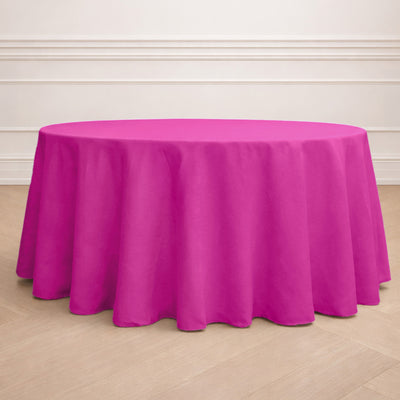 Round pink tablecloth draped over a table set with plates and glasses.