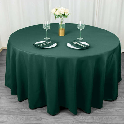Green round tablecloth with elegant table setting and floral centerpiece.