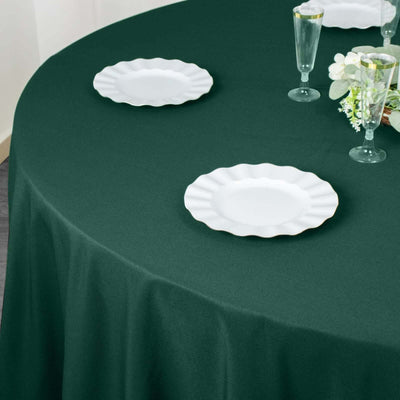 Round green tablecloth with white decorative plates set for dining.
