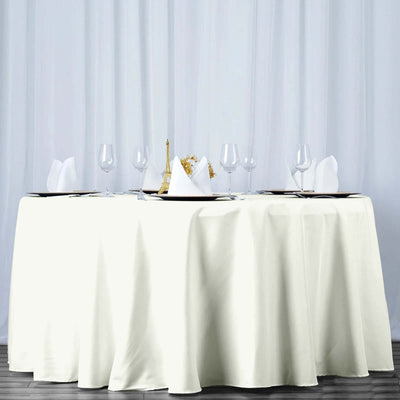 Elegant round table set with white tablecloth and fine dining accessories.