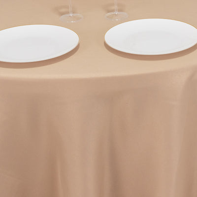Two white plates on a beige tablecloth with wine glasses.