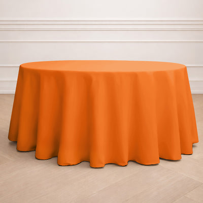 Round orange tablecloth on a wooden floor.