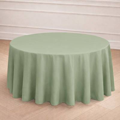 Round green tablecloth draped over a round table in a staged setting.