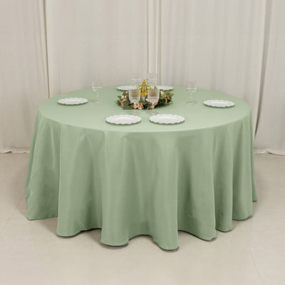 Round mint green tablecloth on a dining table set for a meal.