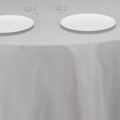Table setting with elegant white plates on a gray tablecloth.