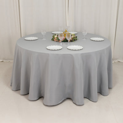 Round gray tablecloth draped over a circular table set for dining.