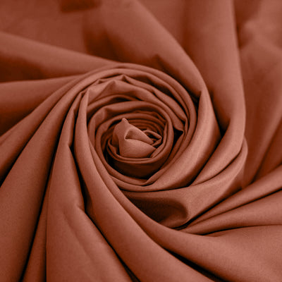 Rust-colored fabric in a smooth, rolled arrangement. #whtbkgd