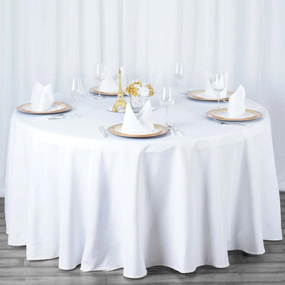 Elegant round dining table set with white linens and decorative elements.