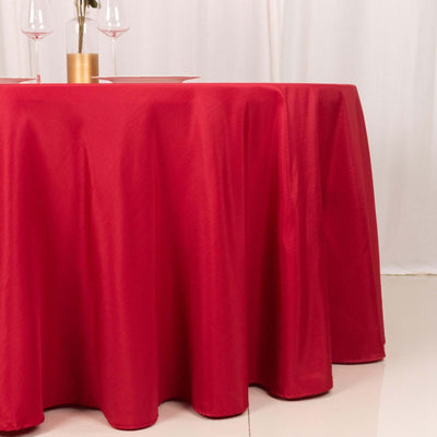 Red tablecloth draping over a round table in a styled setting.