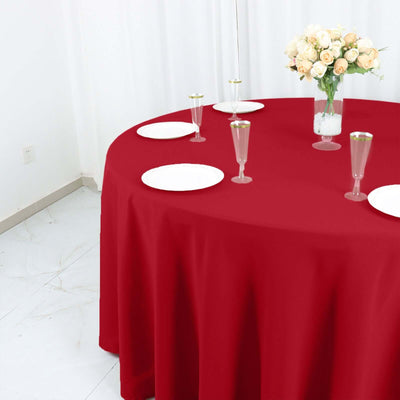 Red tablecloth draped over a round table set with plates and glasses.