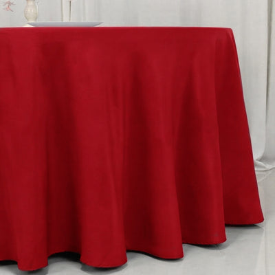 Red round tablecloth draped over a banquet table in a white room