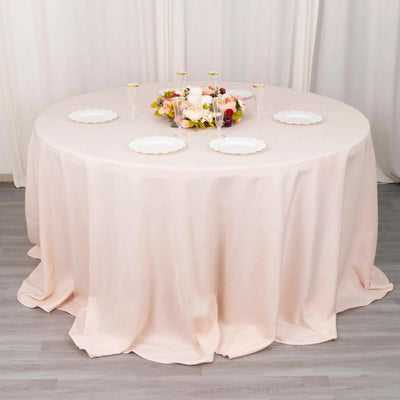 Round blush tablecloth with floral centerpiece and plates.