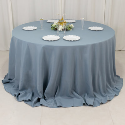 Round blue tablecloth with elegant white plates set for a dining arrangement.
