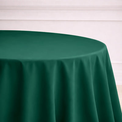 Green round tablecloth draped over a table in a simple setting.