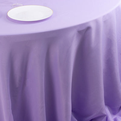 Purple tablecloth draping over a table with a white plate on top.