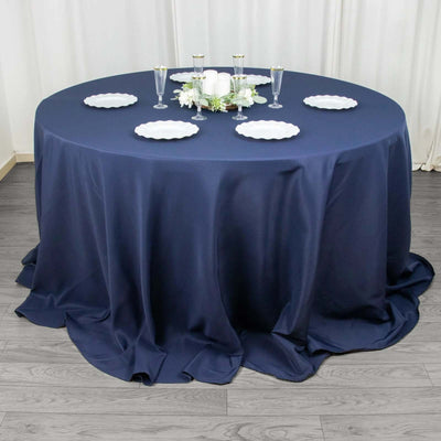 Navy blue tablecloth draped over a round table with plates and glasses