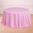 Round pink tablecloth draping over a circular table on a wooden floor.