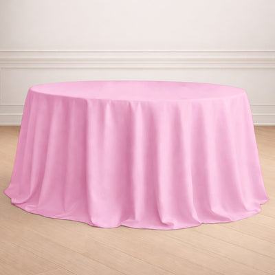 Pink round tablecloth draped over a table in a bright setting.