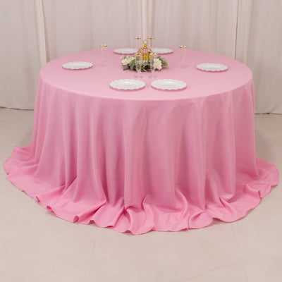 Round pink tablecloth draping elegantly over a circular table with decorative plates.