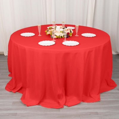 Red round tablecloth with decorative plates and floral centerpiece.