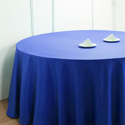 Blue round tablecloth draped over a table with two white dishes on top.
