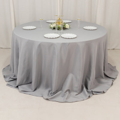 Round gray tablecloth draped elegantly over a circular table with plates and candles.
