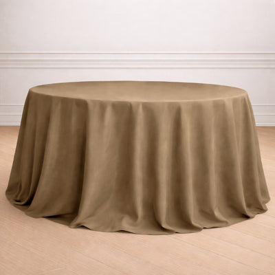 Elegant round table set with brown tablecloth, flowers, and glassware.