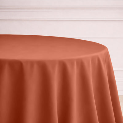 Round terracotta tablecloth draping over a table in a stylish setting.