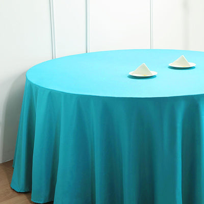 Round turquoise tablecloth draping elegantly over a table with two decorative items.