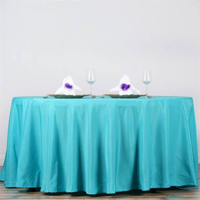 Turquoise tablecloth set for dining with elegant napkin and glassware.