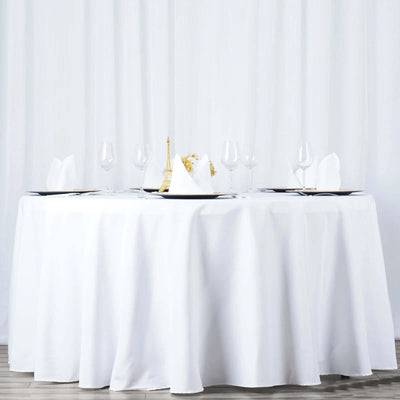 Elegant round table set for dining with white tablecloth and glassware.