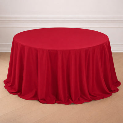 Red round table covered with elegant draped tablecloth in a bright room