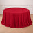 Red round table covered with elegant draped tablecloth in a bright room